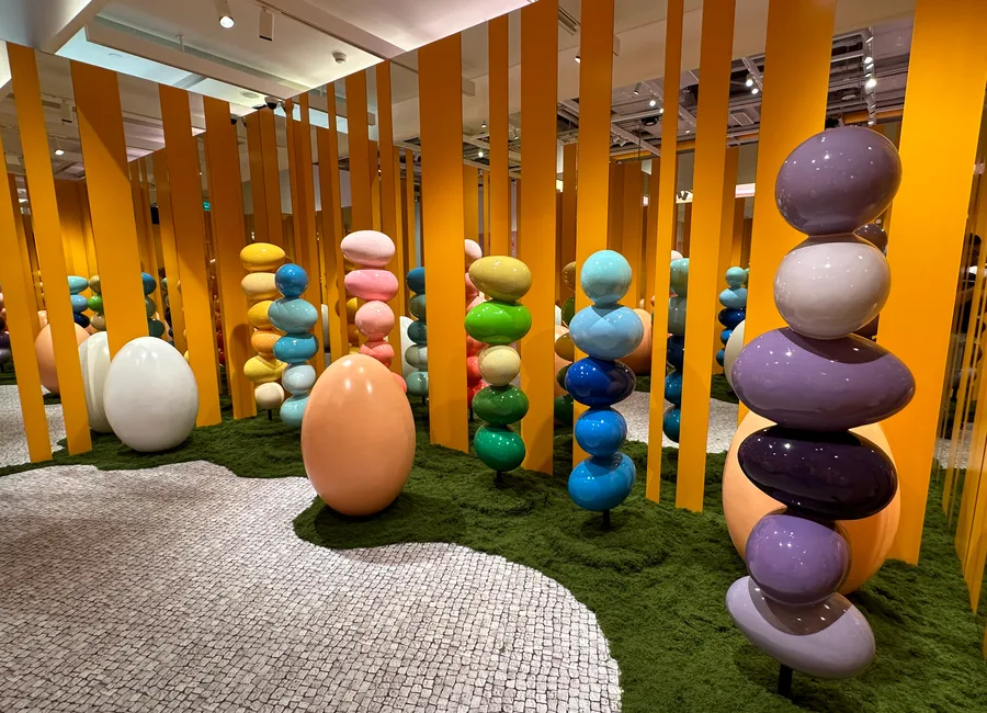 EGG：室內草地上的彩色蛋形雕塑與橙色木柱